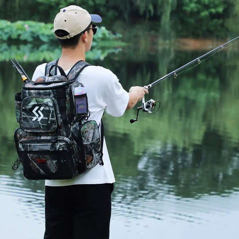 Angler fishing by lake with Camouflage Fishing Tackle Backpack With Four Trays, Waterproof Tackle Box Bag, Rain Cover, And Lanyard