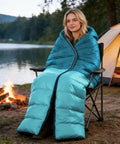 Person sitting by a campfire wrapped in All Weather Sleeping Bag For Adults And Kids, Ultra Lightweight Waterproof Gear For Camping And Hiking