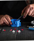 Close-up of hands using a screwdriver on a blue electrical junction box with connectors and components around.