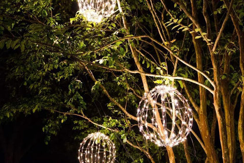 Three Pack 12 Inch LED Globe Lights For Indoor Outdoor Use Waterproof And Durable Warm White Orbs hanging among tree branches at night.