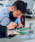 Man soldering on Two Pack Double Sided FR4 PCB Board Set 30 By 20 Cm 1.6 mm Thick Green Prototyping Soldering Board For DIY Electronics Projects