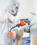 Worker using spray gun wearing Orange Lightning Gloves OR-L Large Work-Ready for industrial medical food service and general use.