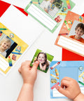 Child placing a photo on 36 Pack Crayon Photo Nameplates for Classroom Desks and Cubbies Self Adhesive Name Tags with Photo Space 4.7 by 4.7 Inches Six Color Designs.