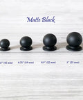 Four sizes of matte black ball knobs on wooden surface, including Solid Brass Matte Black Ball Knob For Cabinets And Drawers Go To Tiny 0.6 Inch Diameter 16 mm Vanity Knob Kitchen Hardware Small Drawer Pull Includes 1 Inch M4 Screw.