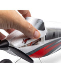 Close-up of hand lifting RC Airplane Apprentice STOL S 700 RTF With AS3X SAFE Technology, showcasing red and white fuselage design