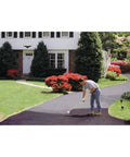 Person applying EZ Stir Rubber Driveway Asphalt Filler Sealer For Cracks Up To One Eighth Inch Quick Patch For Blacktop on driveway