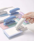 Hand using Pro Grade 40 Sheet Single Hole Punch With Non Slip Base 5.5mm Hole Adjustable Punch Position For Chipboard Cards And Scrapbooks Easy Grip Hand Held Tool Purple on paper