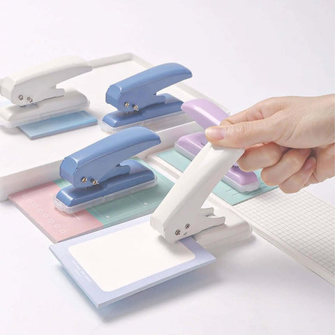 Hand using Pro Grade 40 Sheet Single Hole Punch With Non Slip Base 5.5mm Hole Adjustable Punch Position For Chipboard Cards And Scrapbooks Easy Grip Hand Held Tool Purple on paper