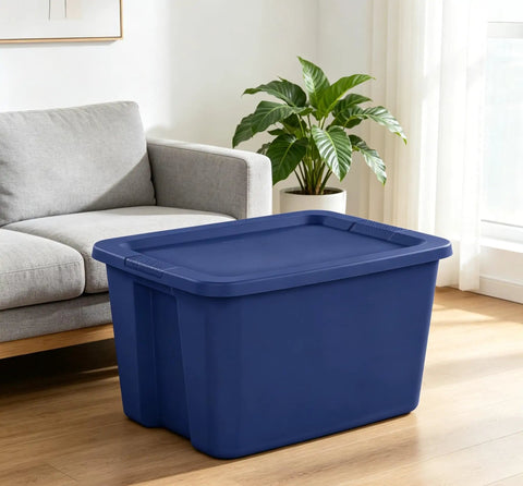 Built Tough 18 Gallon Blue Plastic Storage Tote Bin Featuring A Secure Snap On Lid For Zero Hassle Home Organization And Reliable Gear Storage Year Round beside a sofa in a living room.