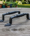 Mystic Colonial Rustic Cast Iron Barn Door Handles Set Of 2 In Black Finish on wooden table, ideal for gates and garden doors.