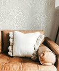 Whimsical Woodland Fantasy Peel And Stick Wallpaper in cream and white on living room wall above tan sofa, USA made.