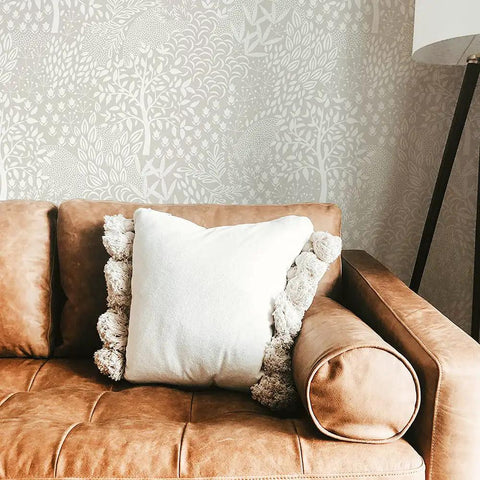 Whimsical Woodland Fantasy Peel And Stick Wallpaper in cream and white on living room wall above tan sofa, USA made.