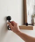 Aolidsive 2 Pcs Magnetic Stud Finder Portable Handheld Wall Stud Detector used on a wall to locate a stud for securing items.