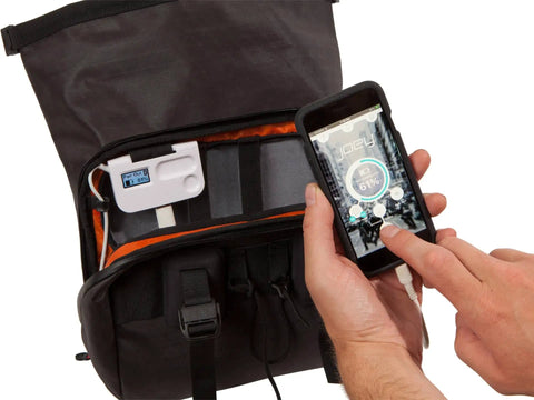 Inside view of Alpha Handlebar Bag 6 Liter for City Commutes and Bike Tours, Weatherproof Messenger With Roll Top And Tech Pocket, Recycled Materials, Black, Integrates With Joey T3 Smartbag Console For Power, Timer, LED Light, And Clock, shown with tech connected to smartphone.