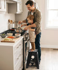 Father and child cooking using a black 16 Inch Folding Step Stool for Home and Apartment Use in the kitchen, supports up to 400 lbs