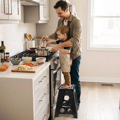Father and child cooking using a black 16 Inch Folding Step Stool for Home and Apartment Use in the kitchen, supports up to 400 lbs