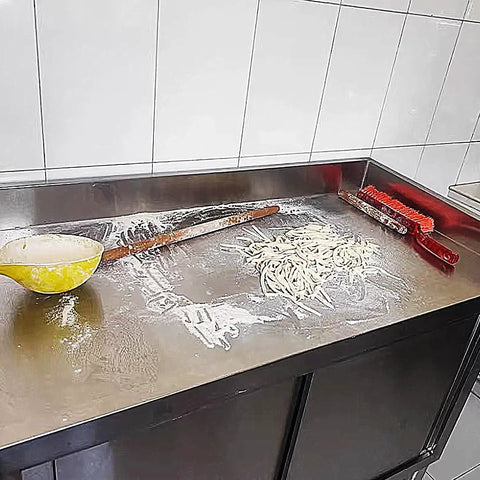Heavy Duty Stainless Steel Prep Table With Cabinet And Splash Guard Slick Commercial Kitchen Workbench Built Like A Tank For Restaurants Or Garages Double Sliding Doors Makes Cleanup A Breeze, showing flour and tools on the surface.