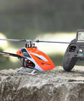 Ready To Fly Pro Grade RC Helicopter With Dual Brushless Motors Direct Drive 6CH Remote resting on a rock outdoors