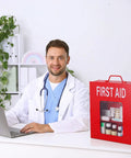 Doctor sitting at desk with red first aid kit, stethoscope around neck, beside Wall Mount First Aid Cabinet With Three Shelves.