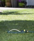 TurboTek 3200 Sq Ft Oscillating Sprinkler with 16 Rubber Nozzles QuickConnect Adapter watering a lawn