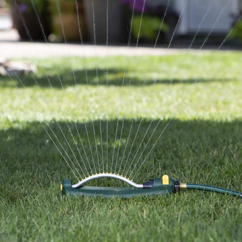 TurboTek 3200 Sq Ft Oscillating Sprinkler with 16 Rubber Nozzles QuickConnect Adapter watering a lawn