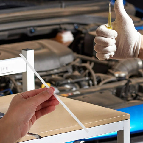 Hand holding a white plastic welding rod in a garage, demonstrating Grab These 10 Pc Plastic Welding Rods For Car Bumper Repair.