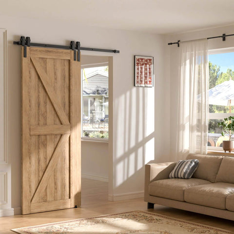 Wooden sliding barn door installed on a track in a sunlit living room next to a sofa and window with curtains.