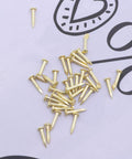 Mini Brass Cabinet Hinges For 1 To 12 Dollhouse Furniture With 48 Screws, shown are small brass screws on a paper background.