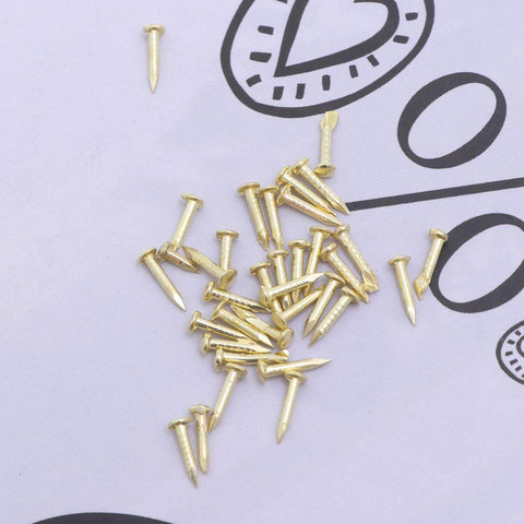 Mini Brass Cabinet Hinges For 1 To 12 Dollhouse Furniture With 48 Screws, shown are small brass screws on a paper background.
