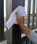 Hand cleaning metal railing with Recycled White T Shirt Cleaning Rags 25 Lb Box Bulk Pack For Oil Stains Grease Paint Auto Cleanup