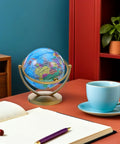 Rotating Desktop Globe With Stand 14.2cm Blue Frame Educational World Sphere on office desk with cup and plant