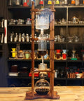 Huge 3 Liter Cold Brew Coffee Maker Serves 25 Cups Of Smooth Iced Tea And Bold Drip Coffee With Zero Hassle Setup showing wooden frame with brewing apparatus.