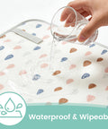 Portable Baby Changing Pad With Waterproof, Wipeable Surface For On The Go Parents shown with water poured on raindrop pattern.