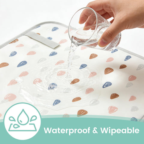 Portable Baby Changing Pad With Waterproof, Wipeable Surface For On The Go Parents shown with water poured on raindrop pattern.