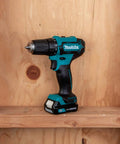 Lightweight 12V Max Cordless Drill Driver And Impact Driver Combo Kit With 1.5Ah Battery displayed on a wooden shelf.
