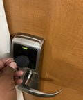 Person using 50 Pcs Pack Re-Writable RFID Hotel Key Fobs For 13.56MHz Locks on a modern door lock