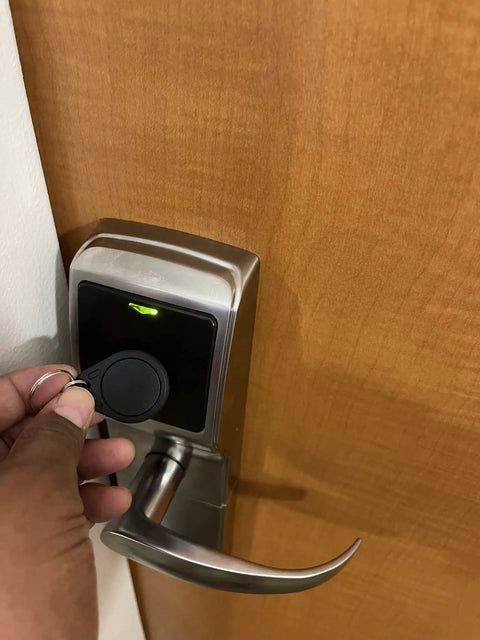 Person using 50 Pcs Pack Re-Writable RFID Hotel Key Fobs For 13.56MHz Locks on a modern door lock
