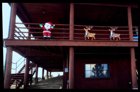 Santa Claus and reindeer decorations on a brown wooden balcony, showcasing festive holiday spirit.