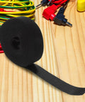 Reusable Black Polyester Cable Ties For Desk Wire Management Heavy Duty Cord Straps For Computer Setup Electronic Organizer on wooden surface.