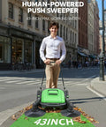 Heavy Duty 43 Inch Industrial Walk Behind Push Floor And Lawn Sweeper clearing leaves in an urban street setting.