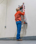 Person using Ladder Storage Rack For Home Garage, Heavy Duty Polymer Mount Keeps Ladders Safe And Accessible, Holds Up To 75 Lbs