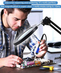 Person using 2 In 1 Magnifying Glass With Light And Stand, 5X Real Glass Lens, 64 LED for repair work at a desk.