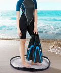 Person standing on Sand Free Wetsuit Changing Mat And Lightweight Beach Bag With Storage Pockets, 110x110 cm at beach.