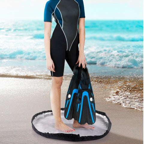 Person standing on Sand Free Wetsuit Changing Mat And Lightweight Beach Bag With Storage Pockets, 110x110 cm at beach.