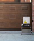 Heavy Duty Automatic Sliding Gate Opener Rigged With Two Remotes And 500W Silent Copper Motor For Driveways Up To 3100 Lbs installed beside a wooden garage door.