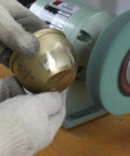 Hand holding brass object near bench grinder using Premium Elastic Polyurethane Buffing Wheels 6 Inch 2000 Grit Silicon Carbide Abrasive.