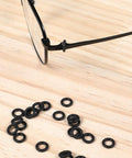 Glasses frame with scattered silicone rings from Three In One Eyeglass Repair Kit With Mini Screwdrivers And 80 Silicone Sealing Rings.