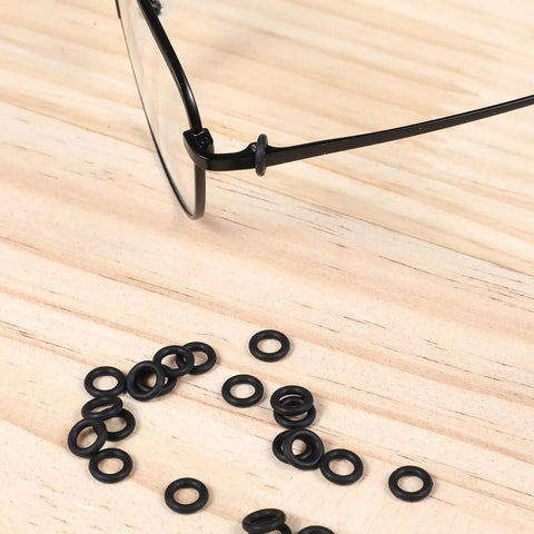 Glasses frame with scattered silicone rings from Three In One Eyeglass Repair Kit With Mini Screwdrivers And 80 Silicone Sealing Rings.