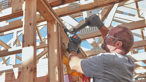 Builder using PROFACTOR 18V Connected Ready Half Inch Hammer Drill and Driver Bare Tool on wooden framework