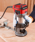 User operating the red Beefy Compact Wood Router With 6.5 Amp 1.25 HP Power, Fixed Base, Includes Trim Bits, on wooden surface